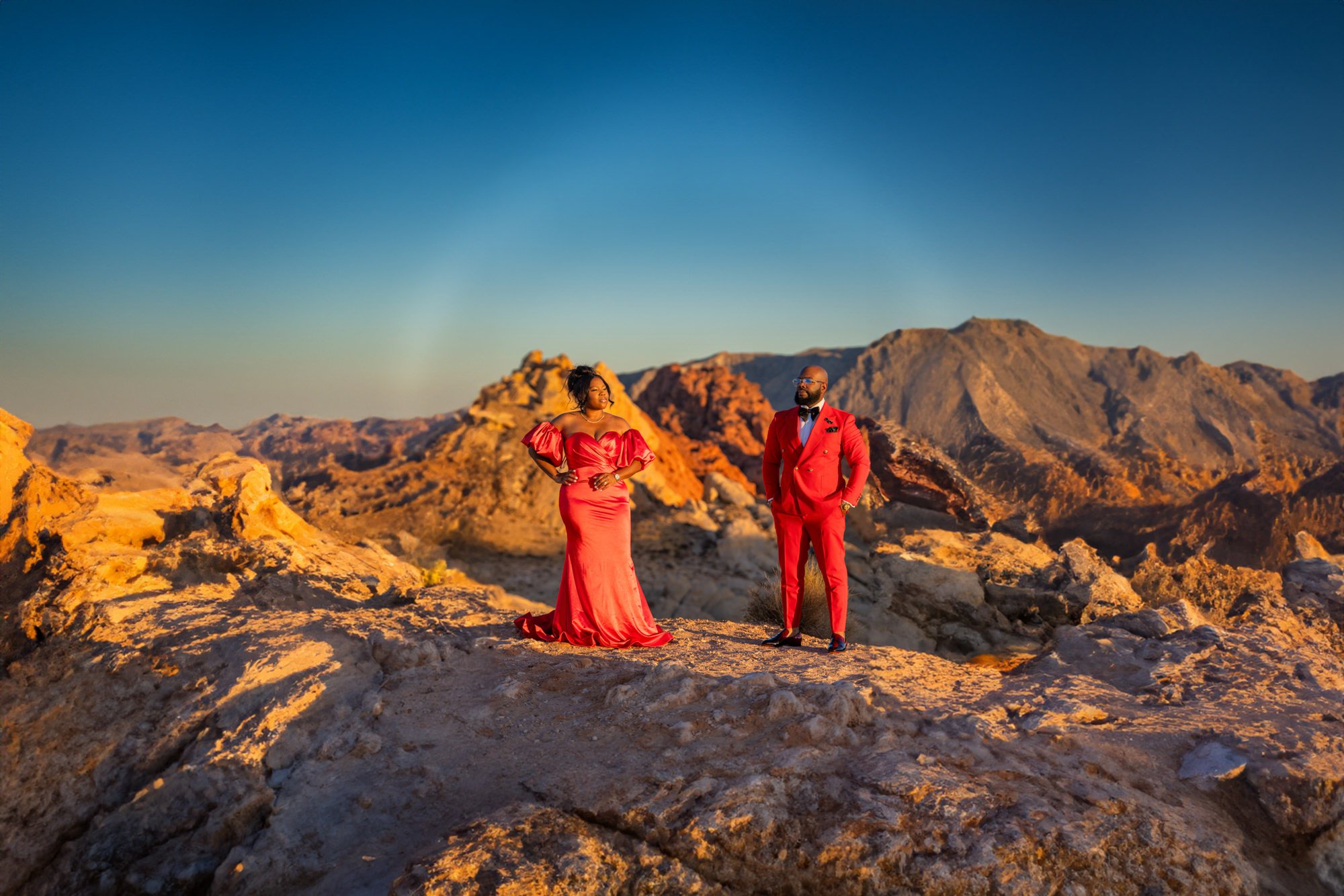 Las Vegas engagement photography — couple in red formal attire on a canyon ridge at sunset